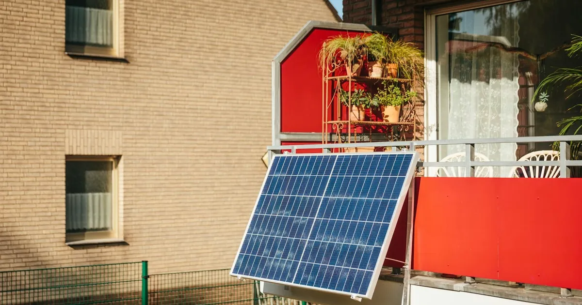 Zonnepaneel aan de balustrade van een stadsbalkon met planten